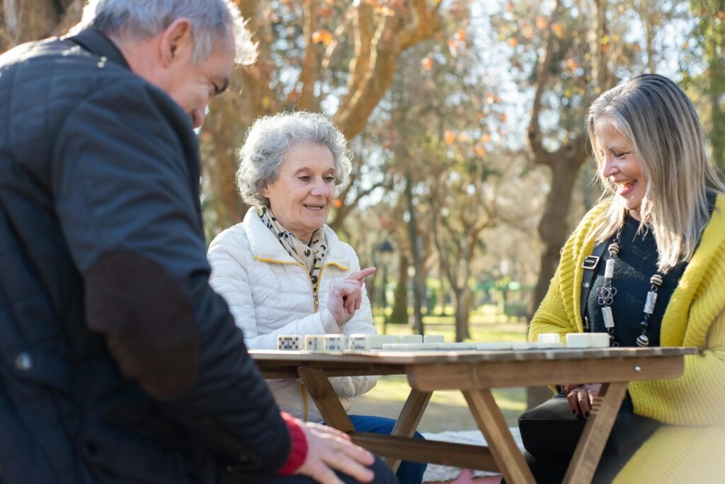 Elderly friends playing dominoes at a park in Portugal, outdoors and enjoying leisure time.
